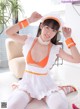 A woman in an orange and white maid outfit posing for the camera.