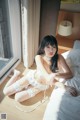 A woman sitting on a bed in a white lingerie.