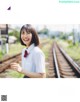 A woman in a white shirt and red tie standing on a train track.