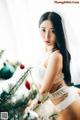 A woman in lingerie posing next to a Christmas tree.