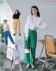 A woman in a white shirt and green pants posing for a magazine.