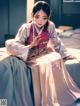 A woman in a kimono sitting on a bed.