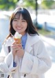 A woman in a white coat holding an ice cream cone.