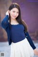 A woman in a blue sweater and white skirt posing for a picture.