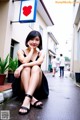 A woman sitting on the ground in front of a building.